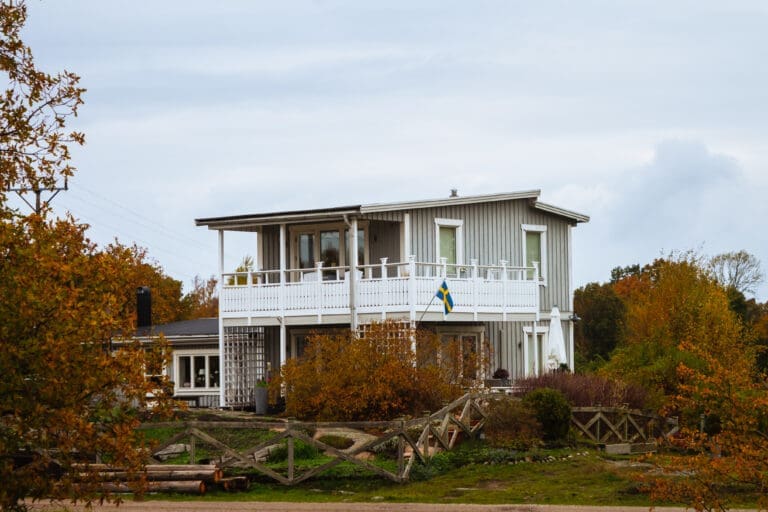 Trähus med svensk flagga under hösten